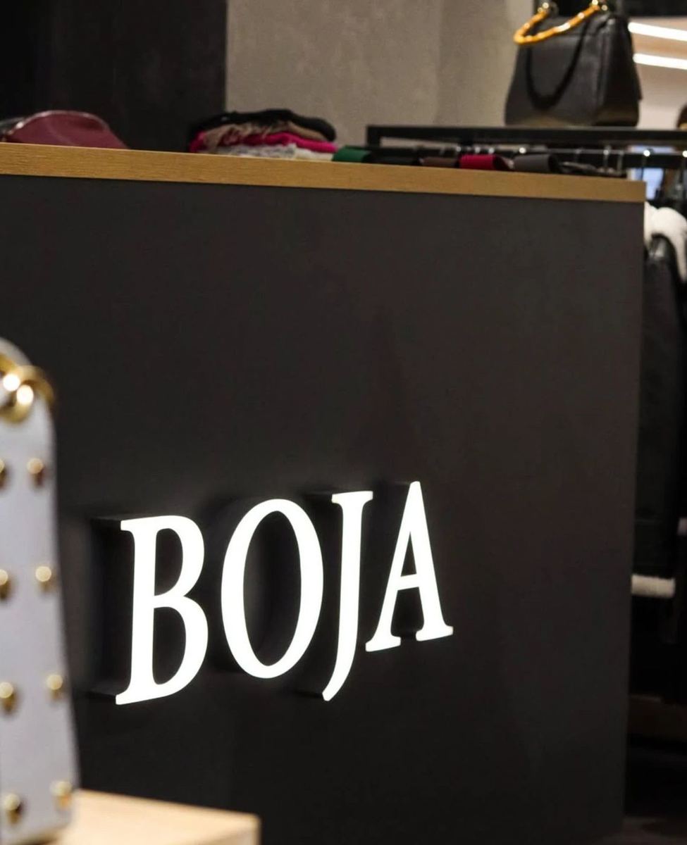 Ocelové 3D logo BOJA s prosvíceným čelem na pultu prodejny